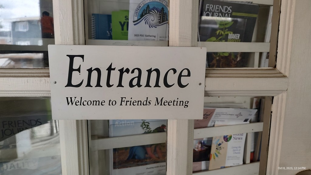 White sign on door with black text reading Entrance, Welcome to Friends Meeting
