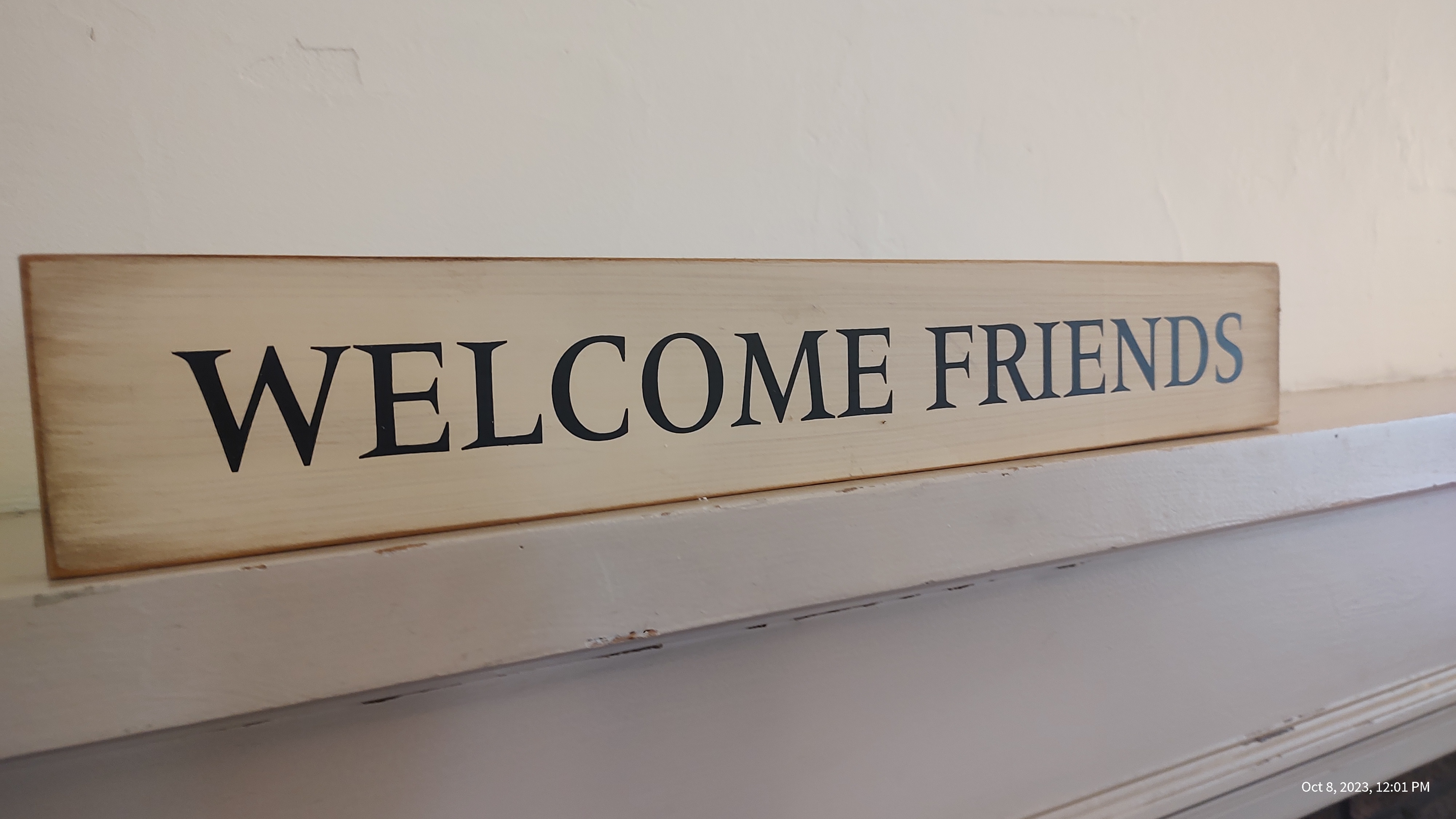 White sign on block of wood that reads Welcome Friends