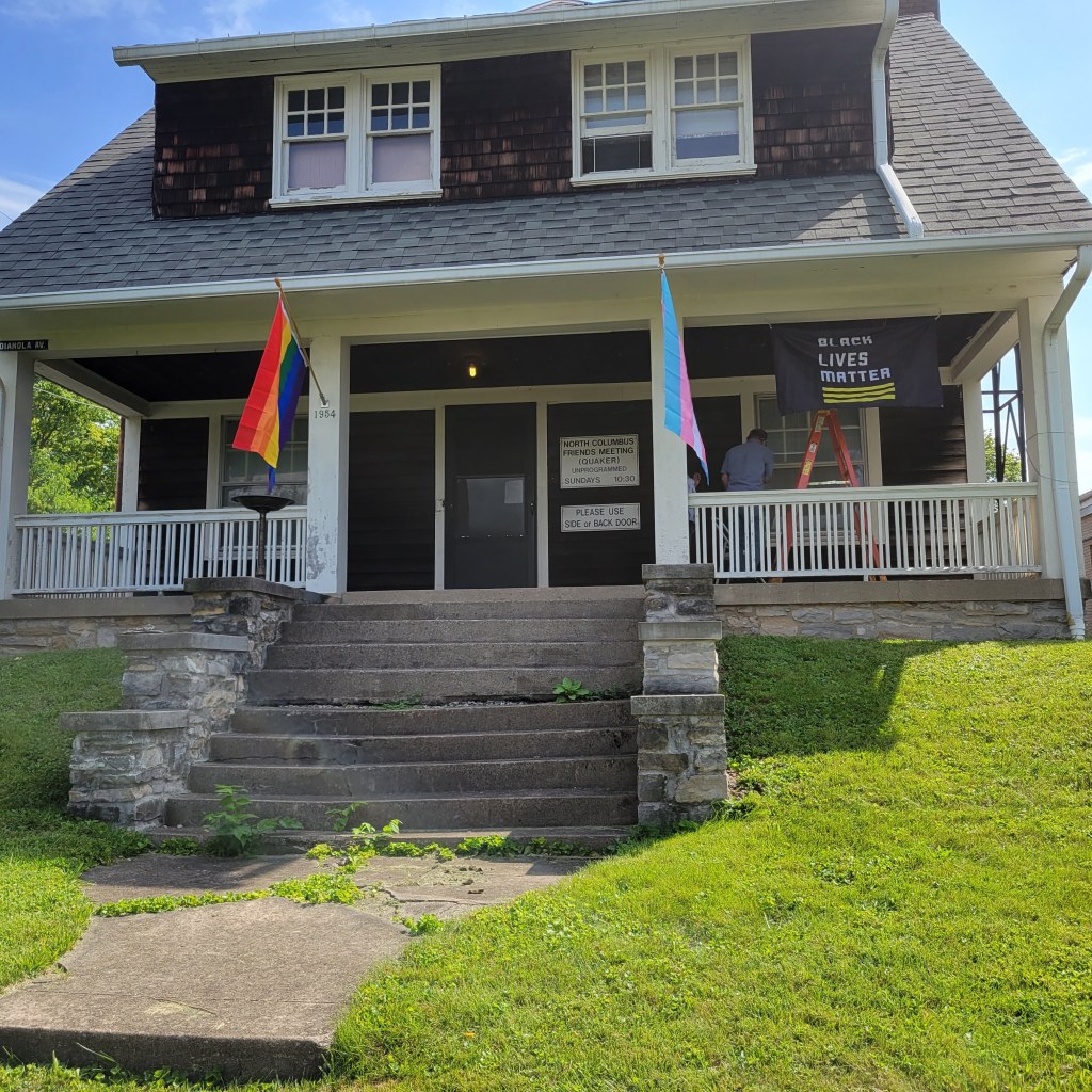 Brown and white house on a hill with flags.