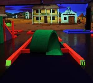 indoor mini golf loop the loop hole 17 with day glo green and orange colors. wild west paiting in background
